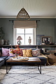 Corner sofa and ethnic accessories in interior with grey walls