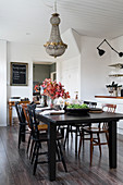 Black dining table and wooden chairs below vintage chandelier in dining area