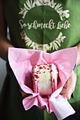 A woman holding a large macaroon with pinked candied nuts (pralines roses)