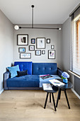 Blue sofa and side tables in narrow living room with grey walls