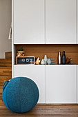 Sitting ball with fabric cover in front of white cupboards with integrated niche shelf