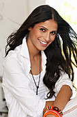 A dark-haired woman wearing a white top and a shirt-blouse