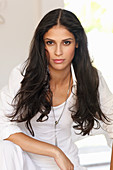 A dark-haired woman wearing a white top and a shirt-blouse