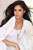 A dark-haired woman wearing a white top and a shirt-blouse