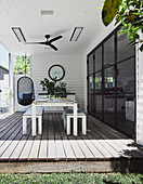 Esstisch und Bänke auf überdachter Terrasse mit Glasfront zum Haus