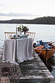 Laid table on a jetty and boat on a lake