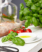 Basil, a bowl of olive oil and tomatoes
