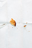 A piece of brioche and crumbs on a white tablecloth