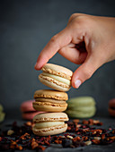 Hand taking a macaron from a pile