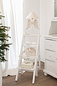 White vintage-style ornaments on white-painted step ladders used as shelves
