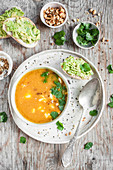 Sweet potato cream soup with cheddar served with guacamole toasts, roasted peanuts and cilantro