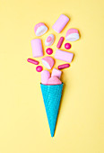 Blaue Eistüte mit rosa Süßigkeiten und Marshmallows