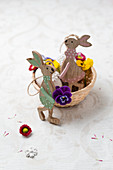Wooden Easter bunnies with tufted pansies and daisies in a basket