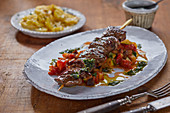 A lamb skewer served with potato gratin (France)