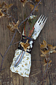 A napkin with cutlery, beechnuts and autumnal leaves