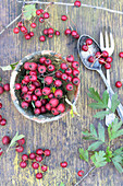Haws in clay pot and cutlery on rustic wooden table