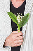 Man holding a bouquet of lily of the valley