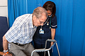 Elderly patient being helped by hospital nurse