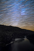 Star trails over river gorge, time-exposure image