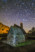 Star trails over Irish monastic chapel, time-exposure image