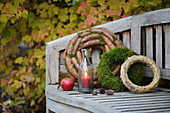 Garden bench decorated with wreaths (moss, fir cones and straw) and candle lantern