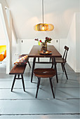 Dining table, stool, chair and bench below sloping ceiling