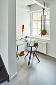 Glass table in niche between window and foot of staircase in renovated Dutch townhouse