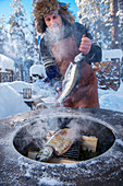 Winter barbecue: a man smoking salmon (Norway)