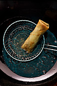 A spring roll in a draining spoon