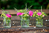 Ländliche Blumensträuße aus Rosen Frauenmantel und Wiesenblumen in Weckgläsern