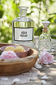 Homemade herbal distillate of rose for use as facial toner in bottle on wooden table