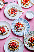 Waffles with cream and strawberries, sprinkled with powdered sugar