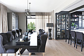 Elegant upholstered chairs around black table in dining area with display cabinet and island counter in background