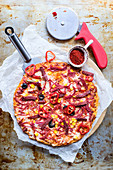 Pikante Pizza mit Würstchen, Mais und Oliven