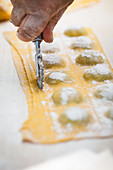 Spinach and ricotta ravioli being cut with a pastry wheel