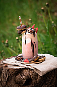 Vegan freakshake made with banana and strawberry ice cream with strawberries and mini doughnuts