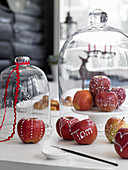 Mit Zuckerguss dekorierte und beschriftete Äpfel unter der Glasglocke