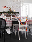 Verschiedene Stühle am schwarzen Tisch mit moderner Weihnachtsdeko