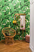 Wicker chair and brass coat stand against Urban Jungle wallpaper