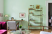 Messing-Regal und filigraner Tisch im Wohnzimmer mit grüner Wand
