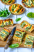 Spring quiche with young vegetables, cut on a wooden board