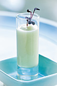 Fenchelcremesuppe mit lila Kresse im Glas vor hellblauem Hintergrund