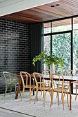 Elongated dining table with bistro chairs in living room with black brick wall