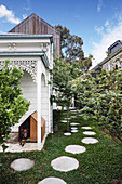 Garden path made of round white stone slabs next to the covered pergola