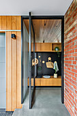 Entrance area with glass swing door and wooden wardrobe with black back wall