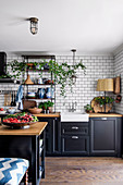 Kitchen with black fronts, white metro tiles and kitchen island