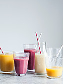 Fruit smoothies in mismatched glasses and bottles with paper straws