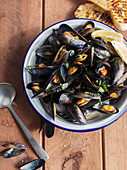 Bowl of Mussels in white wine and garlic on wooden background