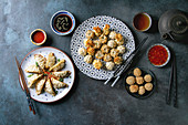 Dim sum Gyozas asian fried dumplings party set with variety of sauces served in ceramic plates and bowls, tea cups and teapot