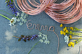 Name formed from copper wire above wild summer flowers